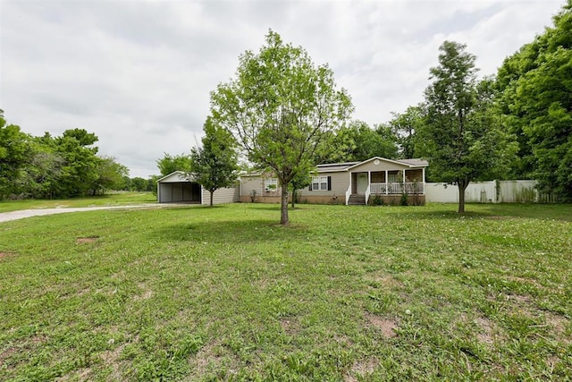 view of yard featuring fence, covered porch, driveway, and a carport