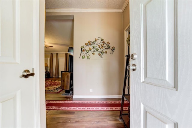 entryway featuring baseboards, ornamental molding, a textured ceiling, and wood finished floors