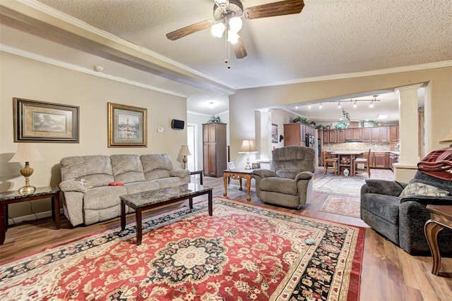 living area featuring ornate columns, a ceiling fan, ornamental molding, and light wood-type flooring
