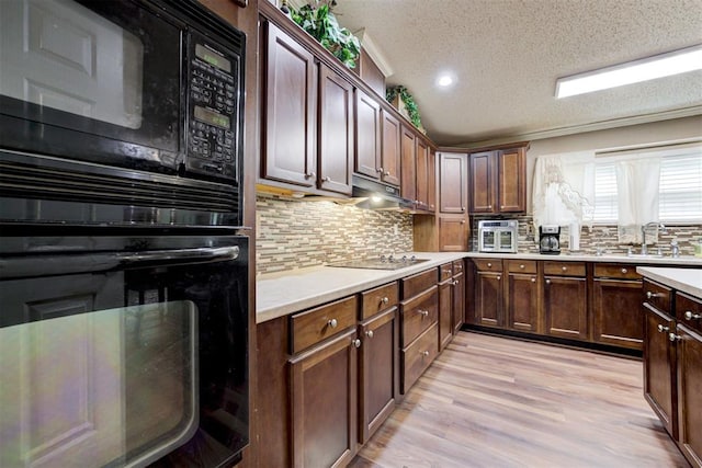 kitchen featuring a sink, a textured ceiling, backsplash, and black appliances