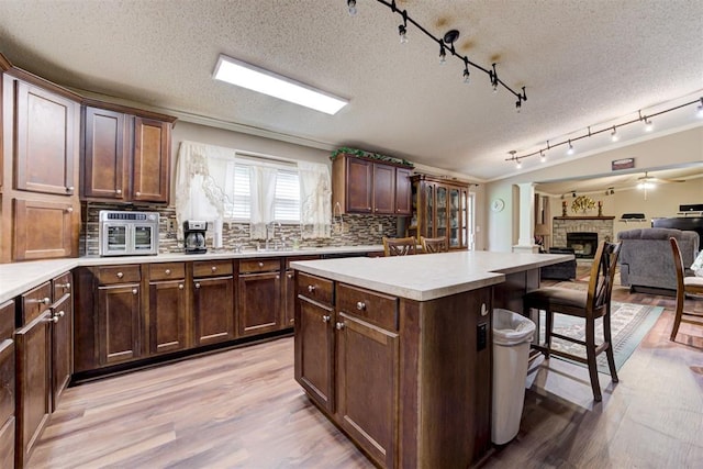 kitchen featuring light wood-style floors, a fireplace, a kitchen island, and a breakfast bar