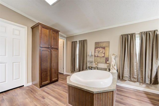 full bath featuring baseboards, ornamental molding, wood finished floors, and a garden tub