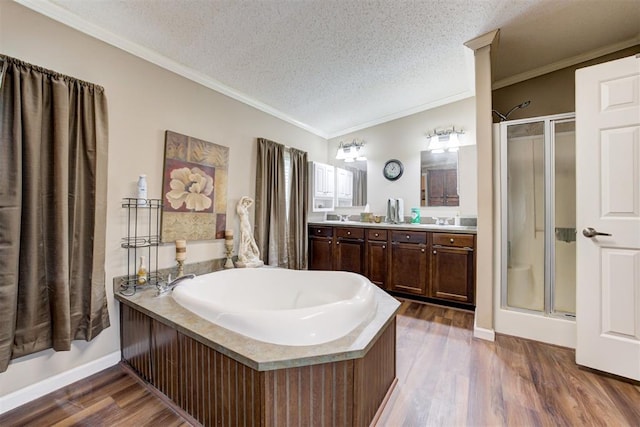 full bathroom with double vanity, wood finished floors, a bath, and a stall shower