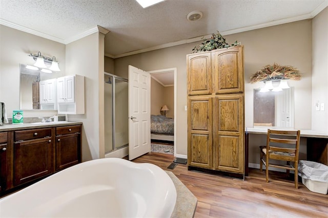 full bath with wood finished floors, ornamental molding, a bathing tub, and a shower stall