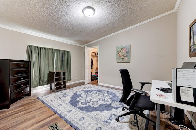 office space featuring light wood-type flooring, a textured ceiling, and crown molding