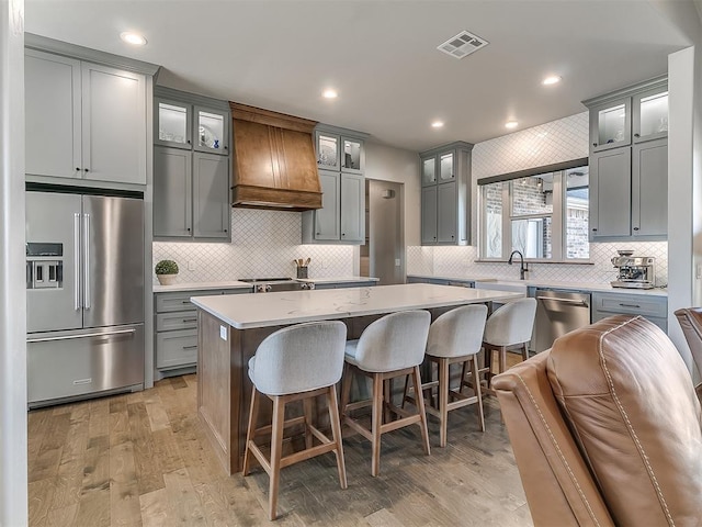 3345 Red Ridge Dr, Blanchard, OK 73010 - kitchen featuring stainless steel appliances, custom range hood, gray cabinetry, decorative backsplash, and recessed lighting