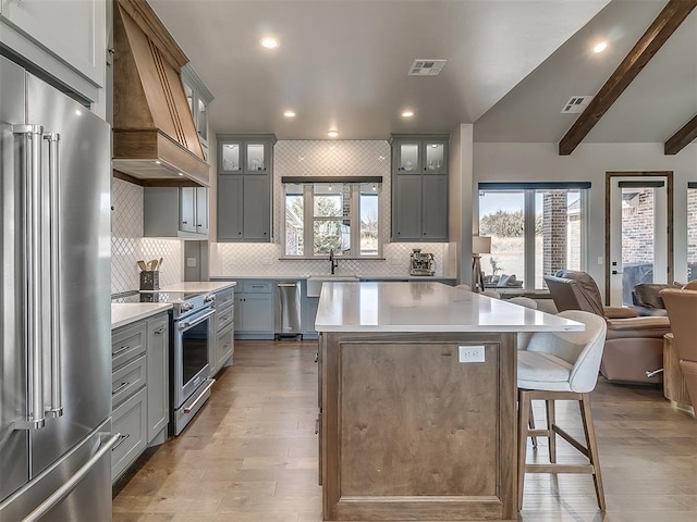 3345 Red Ridge Dr, Blanchard, OK 73010 - kitchen with premium appliances, custom range hood, open floor plan, gray cabinets, and light wood-type flooring