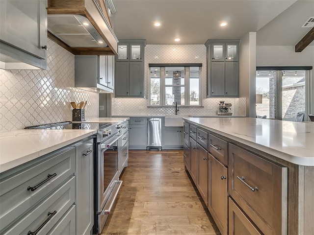 3345 Red Ridge Dr, Blanchard, OK 73010 - kitchen with stainless steel stove, wall chimney range hood, decorative backsplash, a sink, and wood finished floors