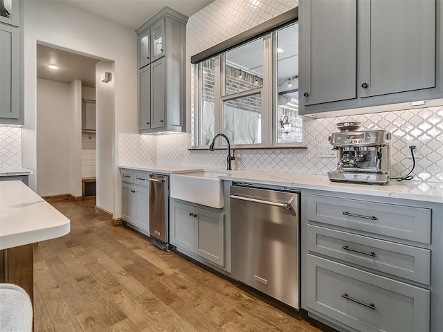 3345 Red Ridge Dr, Blanchard, OK 73010 - kitchen with gray cabinetry, dishwasher, a sink, light wood-type flooring, and decorative backsplash