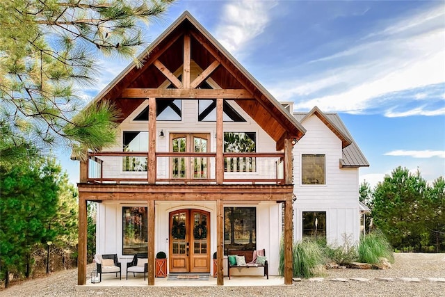 back of property featuring board and batten siding, a balcony, and french doors