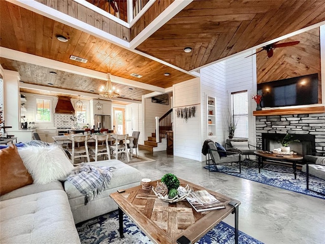 living area featuring wood ceiling, a stone fireplace, visible vents, stairs, and a wealth of natural light