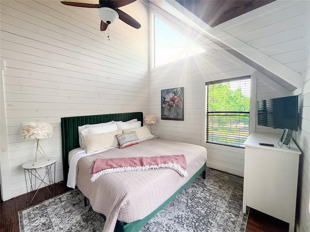 bedroom with a ceiling fan, wooden walls, wood finished floors, and vaulted ceiling