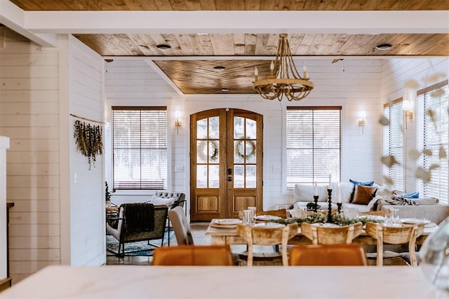 dining area featuring french doors, wood ceiling, wooden walls, and a healthy amount of sunlight