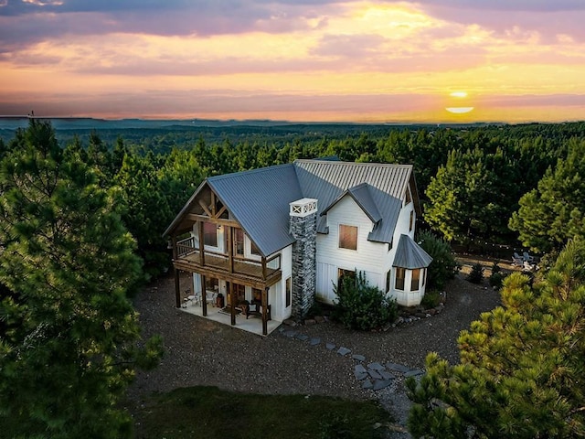 aerial view at dusk featuring a wooded view