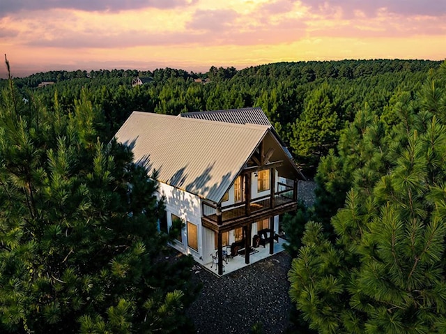 aerial view at dusk featuring a forest view