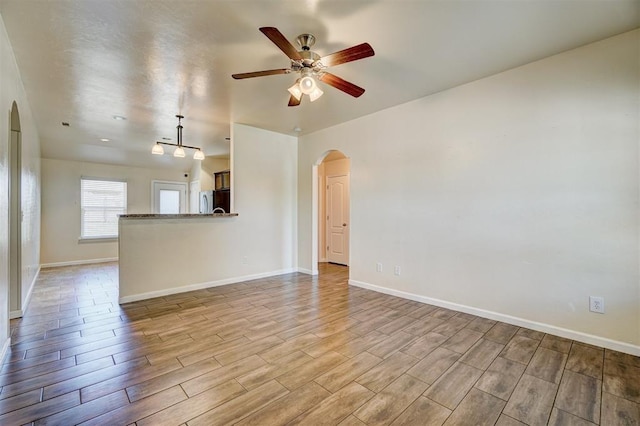 4709 SE 81st St, Oklahoma City, OK 73135 - unfurnished living room with baseboards, wood finished floors, arched walkways, and ceiling fan