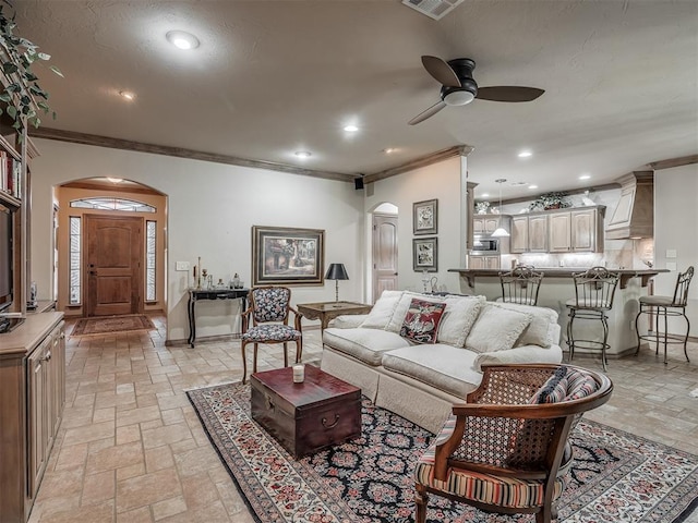 12304 N St Lukes Ln, Oklahoma City, OK 73142 - living room with arched walkways, stone tile flooring, ornamental molding, ceiling fan, and recessed lighting