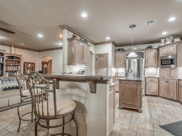12304 N St Lukes Ln, Oklahoma City, OK 73142 - kitchen featuring appliances with stainless steel finishes, arched walkways, crown molding, stone tile flooring, and a kitchen breakfast bar