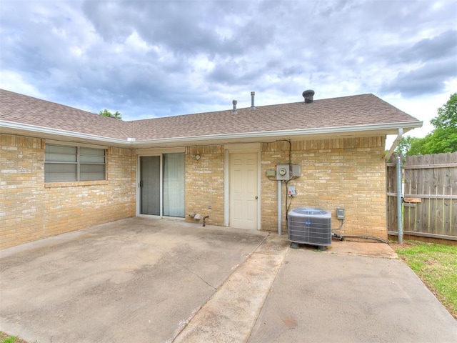 1703 Surrey Pl, Norman, OK 73071 - back of house featuring brick siding, a patio, fence, central air condition unit, and roof with shingles