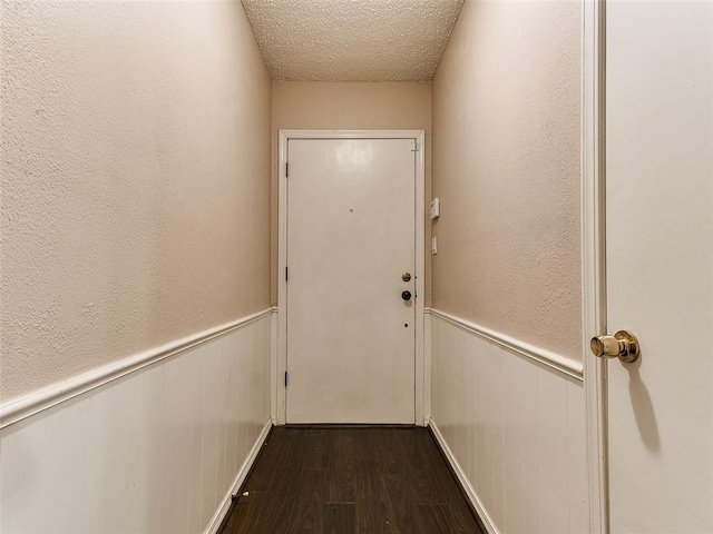 1703 Surrey Pl, Norman, OK 73071 - doorway with dark wood-type flooring, wainscoting, and a textured ceiling