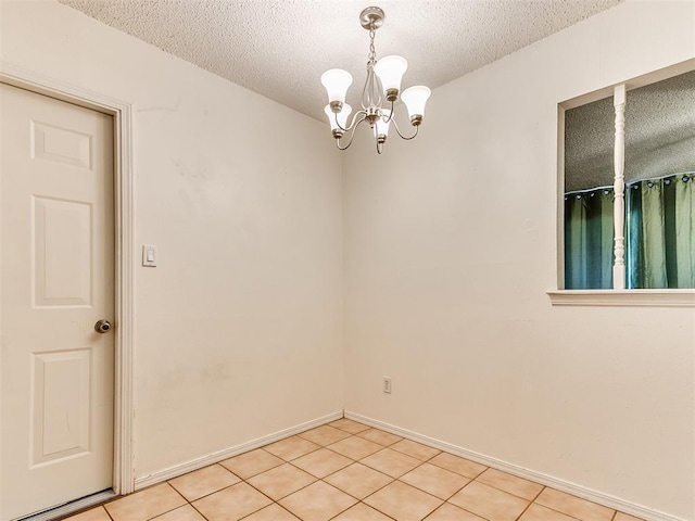 1703 Surrey Pl, Norman, OK 73071 - spare room with a textured ceiling, a chandelier, light tile patterned flooring, and baseboards