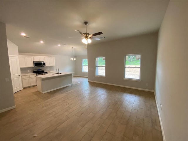20640 Brush Creek Blvd, Harrah, OK 73045 - kitchen with stainless steel microwave, stove, open floor plan, light wood-style flooring, and white cabinets
