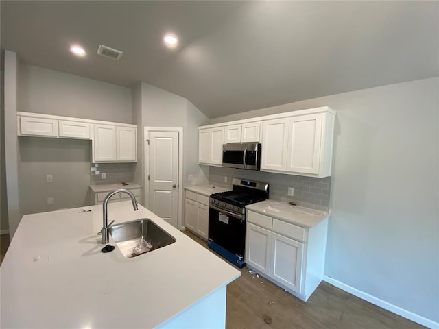 20640 Brush Creek Blvd, Harrah, OK 73045 - kitchen featuring stainless steel appliances, tasteful backsplash, white cabinetry, wood finished floors, and lofted ceiling