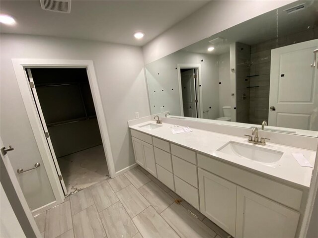 20640 Brush Creek Blvd, Harrah, OK 73045 - bathroom featuring double vanity, tiled shower, recessed lighting, and a walk in closet