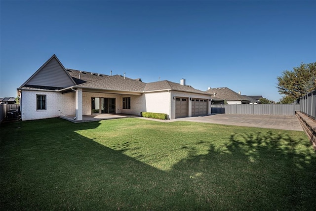 back of property with a yard, an attached garage, and a fenced backyard