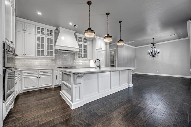 kitchen featuring tasteful backsplash, light countertops, premium range hood, double oven, and white cabinets