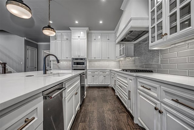 kitchen featuring custom exhaust hood, stainless steel appliances, light countertops, a sink, and white cabinetry