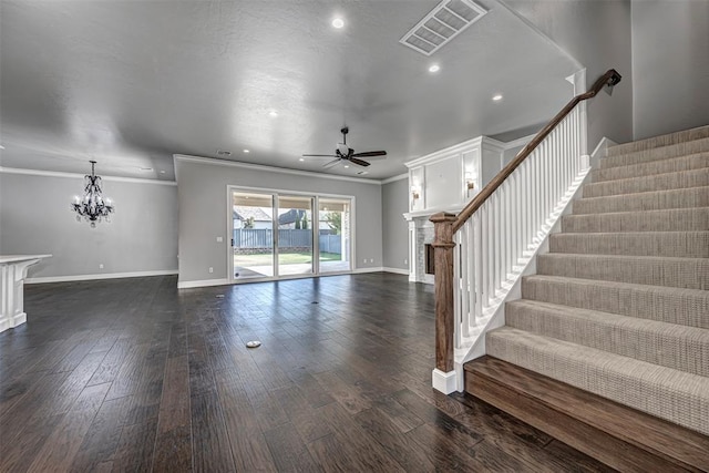 unfurnished living room featuring ornamental molding, ceiling fan with notable chandelier, a fireplace, baseboards, and visible vents