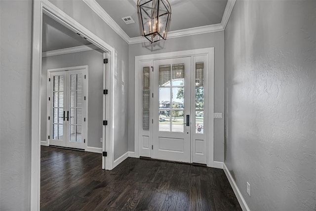 foyer entrance with a notable chandelier, visible vents, a textured wall, ornamental molding, and dark wood finished floors