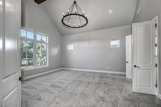 carpeted empty room with lofted ceiling, visible vents, a notable chandelier, and baseboards
