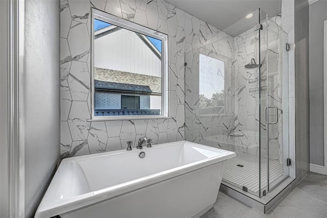 bathroom with a soaking tub, a shower stall, and tile walls