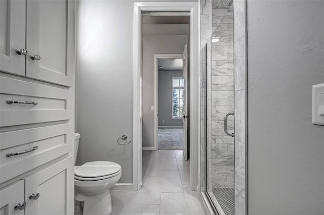 bathroom with baseboards, tile patterned floors, a shower stall, and toilet