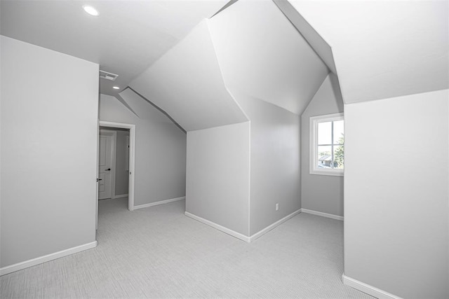 additional living space featuring carpet, visible vents, vaulted ceiling, and baseboards