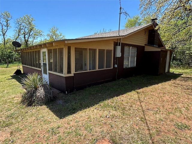 view of home's exterior with a lawn, a sunroom, and roof with shingles