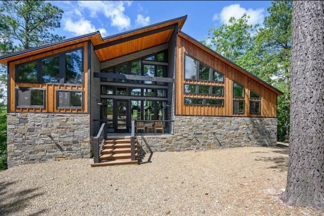 view of exterior entry with stone siding and board and batten siding