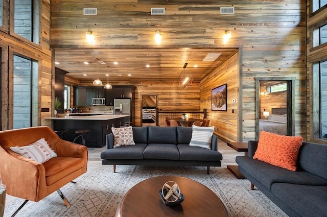living room featuring wooden walls, lofted ceiling, and visible vents