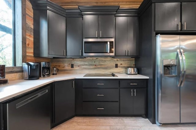 kitchen featuring light countertops, light wood-style flooring, wood walls, and stainless steel appliances