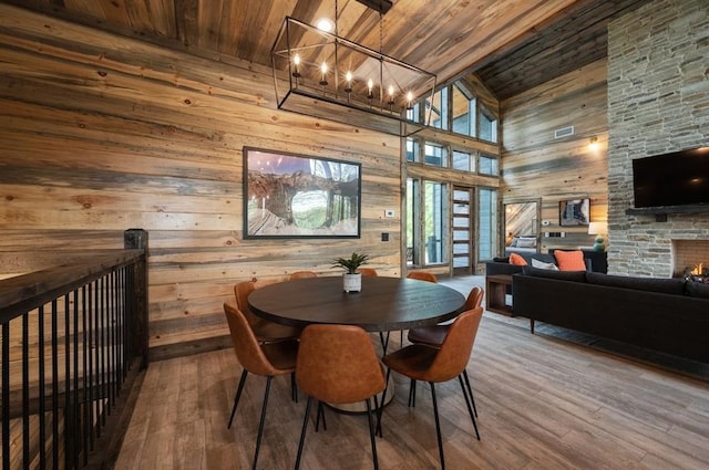 dining room featuring wood walls, wooden ceiling, a high ceiling, and a chandelier