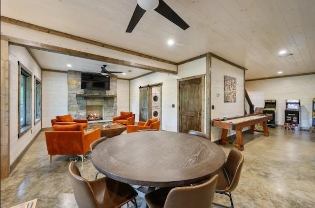 dining space featuring a fireplace, beam ceiling, a ceiling fan, and finished concrete floors