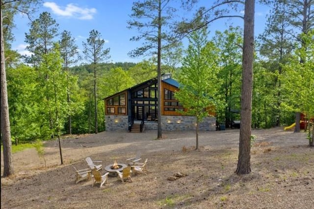 exterior space featuring a wooded view and an outdoor fire pit