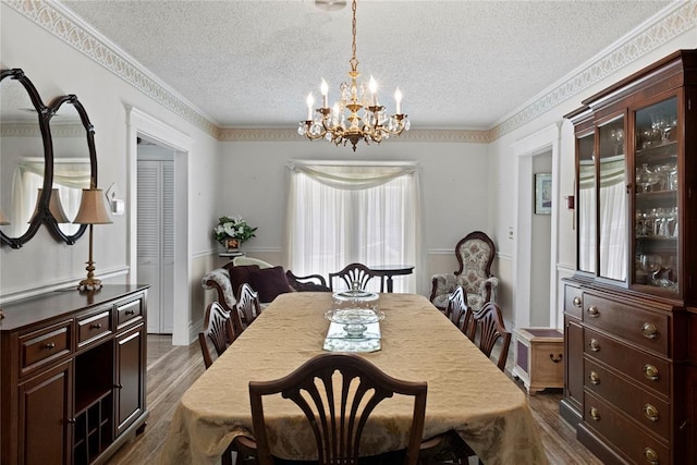 dining room featuring an inviting chandelier, ornamental molding, a textured ceiling, and dark wood-style floors