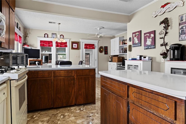 kitchen featuring a peninsula, a textured ceiling, visible vents, white appliances, and light countertops
