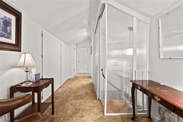 hallway featuring lofted ceiling, a textured ceiling, and light carpet