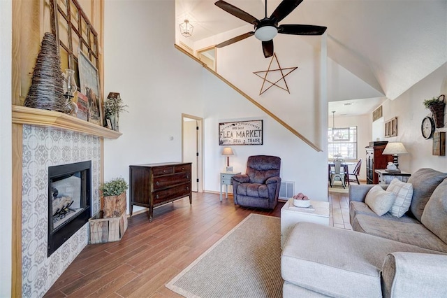 1409 SW 23rd St, Moore, OK 73170 - living room with visible vents, a ceiling fan, wood finished floors, a tile fireplace, and high vaulted ceiling