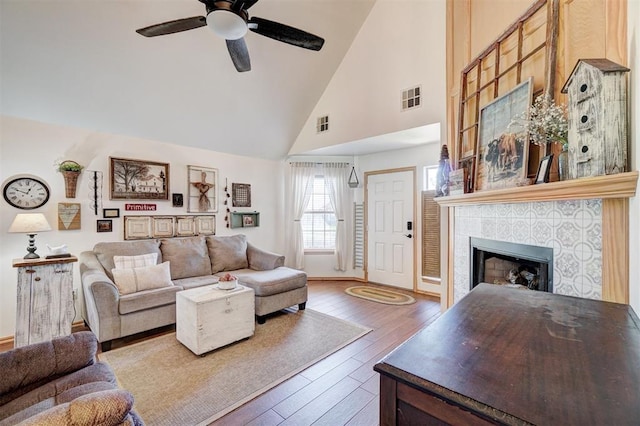 1409 SW 23rd St, Moore, OK 73170 - living room with hardwood / wood-style floors, visible vents, a tiled fireplace, high vaulted ceiling, and ceiling fan