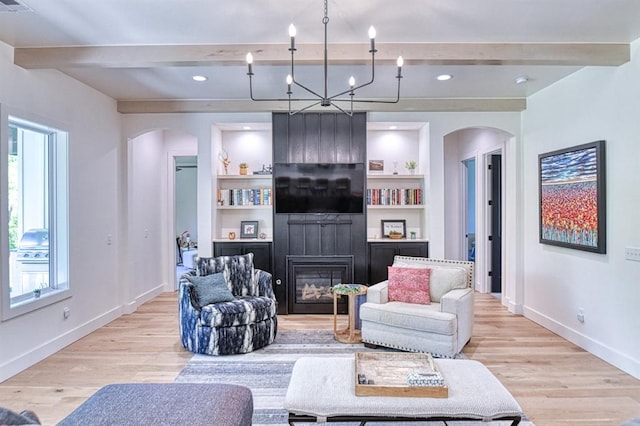 living room featuring beam ceiling, a wealth of natural light, light wood-style floors, and arched walkways